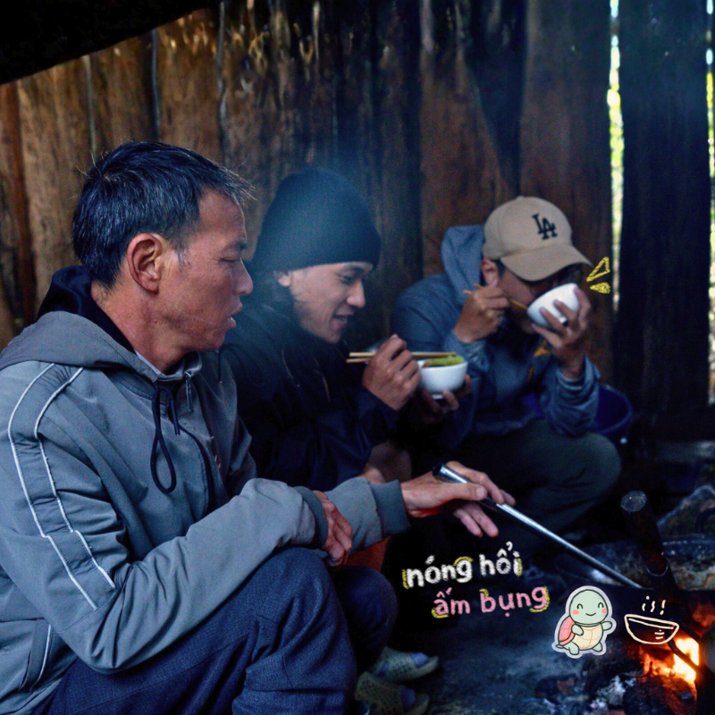 Anh khách ngồi trong căn bếp nhỏ ấm cúng tại lán nghỉ trên đường leo núi Putaleng, chú porter người địa phương đang nấu bữa ăn nóng hổi thơm lừng trên bếp củi